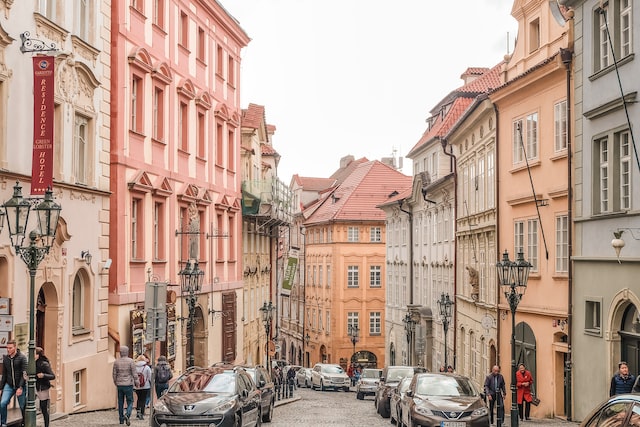 Cars parked beside brown and pink concrete buildings during the day in Prague.
